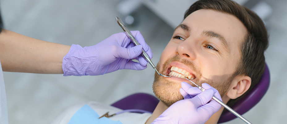 Male patient smiling during a dental examination with tools, highlighting professional and gentle care at a dentist in National City CA - Dentist National City CA