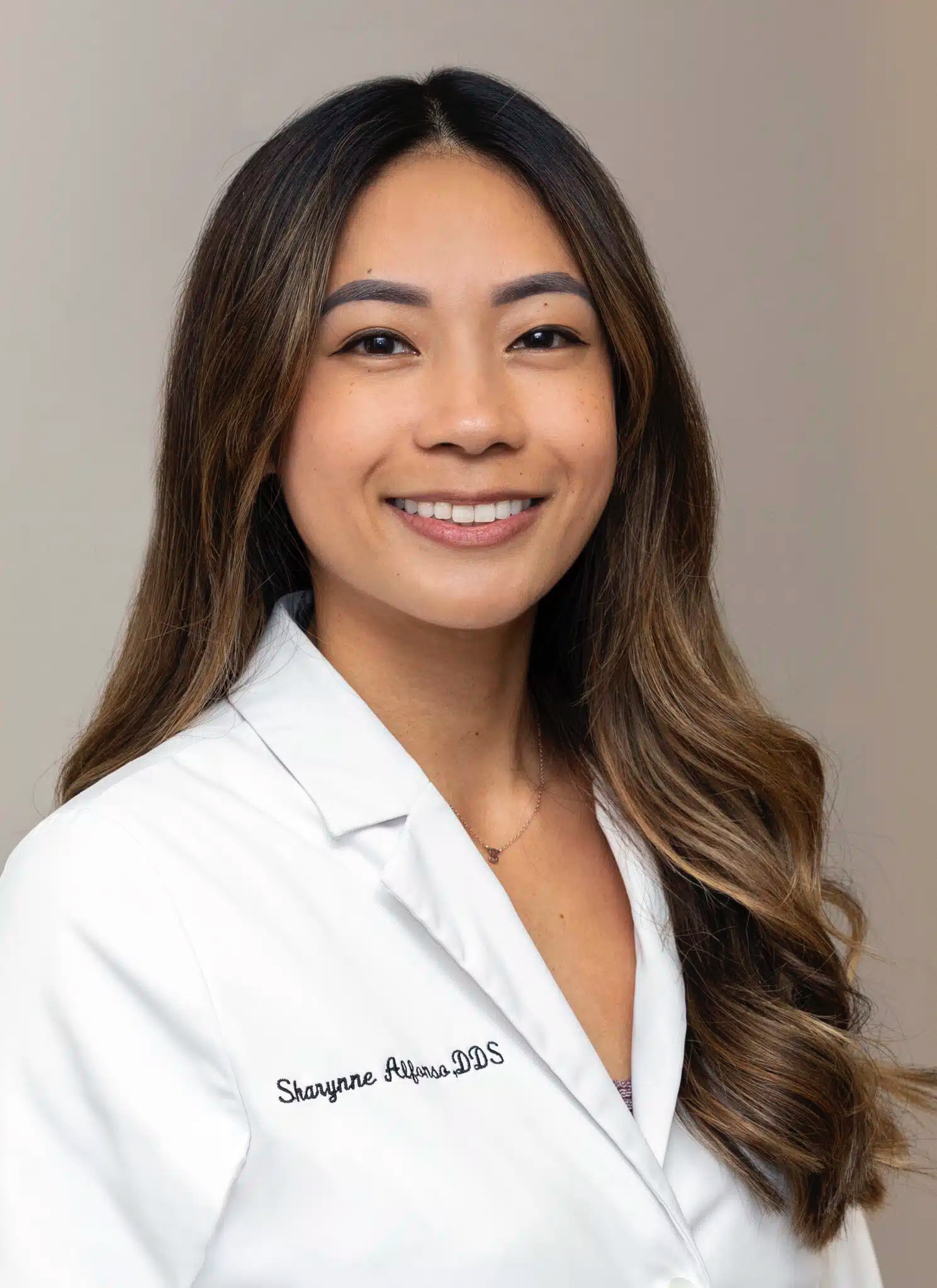 Portrait of Dr. Sharynne Alfonso DDS in a white coat smiling confidently, representing a skilled and welcoming dentist in National City CA - Dentist National City CA